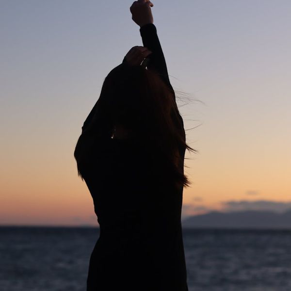 Silhouette of a man stretching against a sunrise, symbolizing well-being.